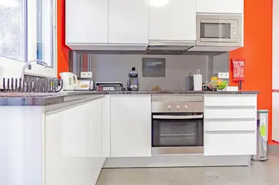 a kitchen with white cabinets and an orange wall at Harmony Apartment in Funchal