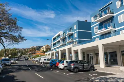 a blue building with cars parked in a parking lot at Sun and Sea II in Caniço