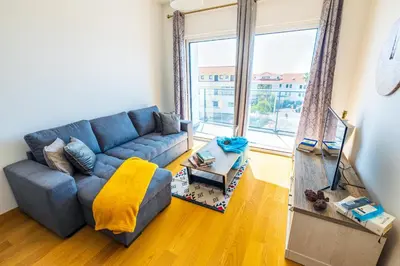 a living room with a blue couch and a large window at Sun and Sea II in Caniço