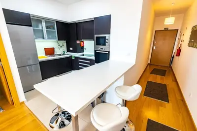 a kitchen with a white counter and white chairs at Sun and Sea I in Caniço