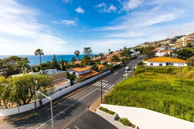 a street in a town with the ocean in the background at Sun and Sea I in Caniço