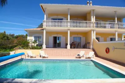 a villa with a swimming pool in front of a house at Vila G, Mira Luz in Luz