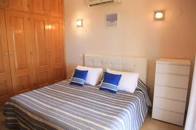 a bedroom with a bed with blue and white pillows at Vila G, Mira Luz in Luz