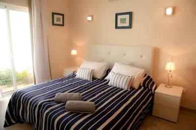 a bedroom with a blue and white striped bed with two pillows at Vila G, Mira Luz in Luz