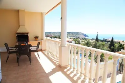 a balcony with a table and chairs and a view of the ocean at Vila G, Mira Luz in Luz