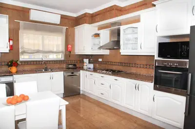 a large white kitchen with white cabinets and appliances at Vila G, Mira Luz in Luz