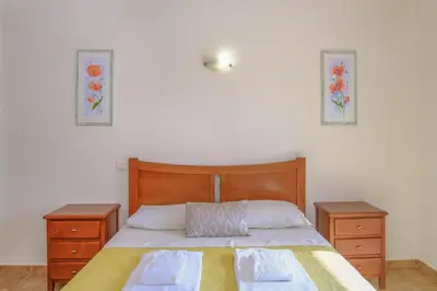 a bedroom with a bed with two dressers and two pictures on the wall at Vila Bela Nova Acácias 22 in Luz
