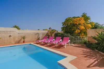 a swimming pool with pink chairs next to a swimming pool at Vila Bela Nova Acácias 22 in Luz