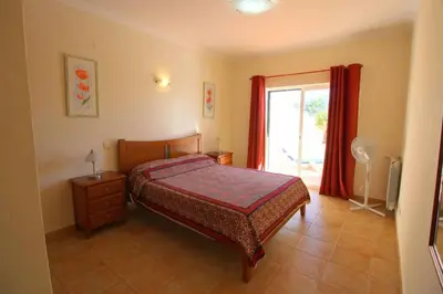 a bedroom with a bed and a large window at Vila Bela Nova Acácias 22 in Luz