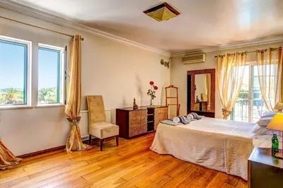 a bedroom with a bed and a chair and windows at Villa Daisy by Villa Plus in Lagos