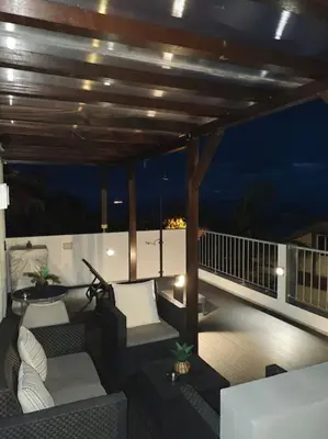 a deck with couches and chairs on a balcony at night at Vаrаndаs dо Sоl-Vista relaxante entre mar e montanha in Ponta do Sol