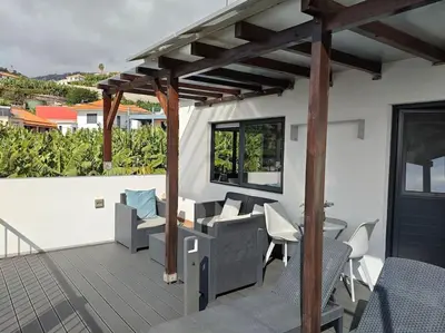 a wooden deck with chairs and a pergola at Vаrаndаs dо Sоl-Vista relaxante entre mar e montanha in Ponta do Sol