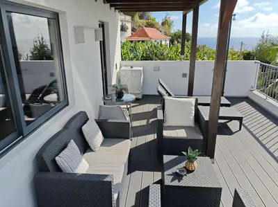 a patio with chairs and a table on a deck at Vаrаndаs dо Sоl-Vista relaxante entre mar e montanha in Ponta do Sol
