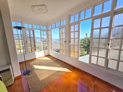 an empty room with large windows and a floor lamp at Maria Cottage Levada do Norte WiFi in Câmara de Lobos