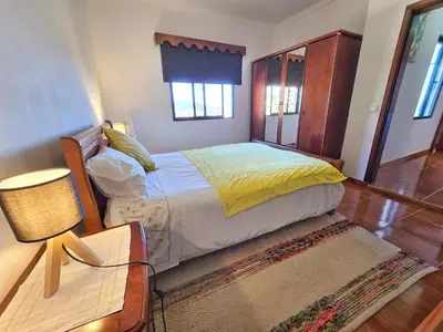 a bedroom with a bed and a table with a lamp at Maria Cottage Levada do Norte WiFi in Câmara de Lobos