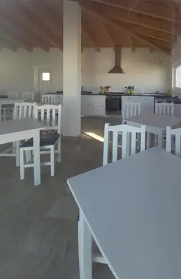 a white kitchen with white tables and white chairs at Monte Bagão - Turismo Rural in Vila do Bispo