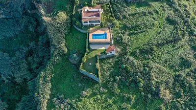 an aerial view of a house in a forest at Secluded Sunset Villa on Cliff & 180 Degree Ocean Views in Fajã da Ovelha