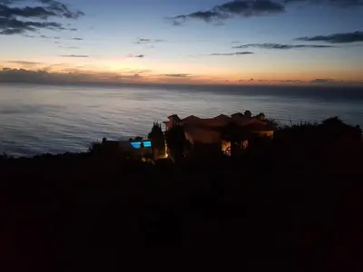 a group of people standing on a hill near the ocean at Secluded Sunset Villa on Cliff & 180 Degree Ocean Views in Fajã da Ovelha