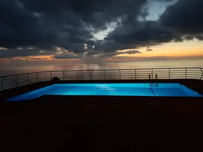 a swimming pool on top of a cruise ship at sunset at Secluded Sunset Villa on Cliff & 180 Degree Ocean Views in Fajã da Ovelha