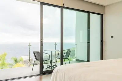a bedroom with a view of the ocean at Sunshine Villa with Optionally Heated Pool 150m above Ocean & Sandy Beach in Estreito da Calheta
