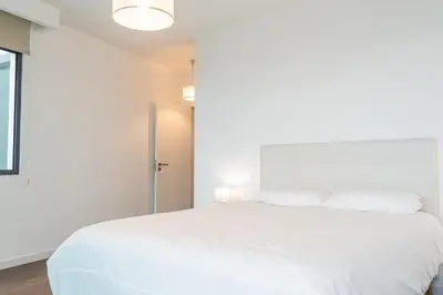 a bedroom with a white bed with white pillows at Sunshine Villa with Optionally Heated Pool 150m above Ocean & Sandy Beach in Estreito da Calheta