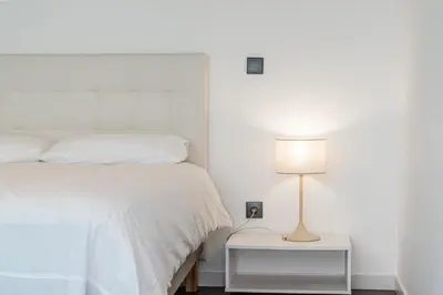 a bedroom with a white bed and a lamp at Sunshine Villa with Optionally Heated Pool 150m above Ocean & Sandy Beach in Estreito da Calheta
