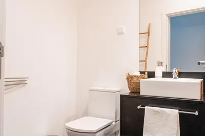 a bathroom with a white toilet and a sink at Sunshine Villa with Optionally Heated Pool 150m above Ocean & Sandy Beach in Estreito da Calheta