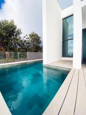 a swimming pool with blue water in front of a house at Sunshine Villa with Optionally Heated Pool 150m above Ocean & Sandy Beach in Estreito da Calheta