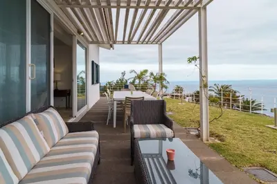 a patio with a couch and a table with a view of the ocean at Vila da Falésia-With Pool and views in Caniço