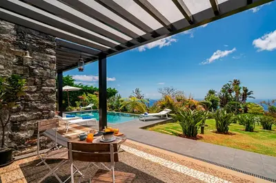 a patio with a table and chairs and a pool at OurMadeira - Garden Paradise in Calheta