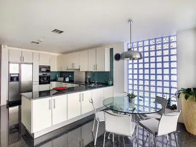 a kitchen with a glass table and white cabinets at The White House - By LovelyStay in Funchal