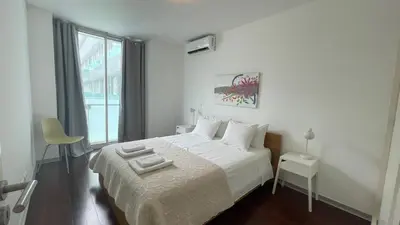 a white bedroom with a bed and a window at Funchal Centrum Apartment in Funchal