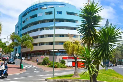 a blue building on a city street with a palm tree at Sol do Lido in Funchal