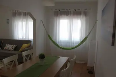 a living room with a green hammock hanging from the window at Casa das Flores in Vila do Bispo