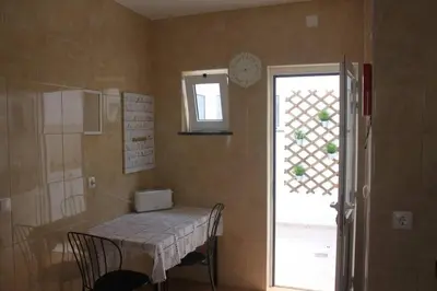 a room with a table and a window and a clock at Casa das Flores in Vila do Bispo
