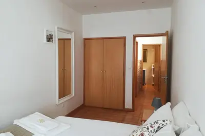 a white bedroom with a bed and a bathroom at Casa das Flores in Vila do Bispo