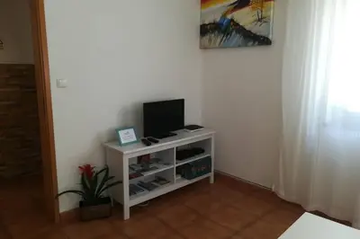 a small white cabinet with a television on it at Casa das Flores in Vila do Bispo