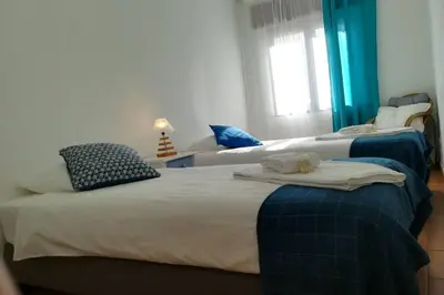 three beds in a room with blue and white at Casa das Flores in Vila do Bispo