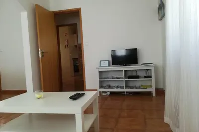 a living room with a white table and a tv at Casa das Flores in Vila do Bispo
