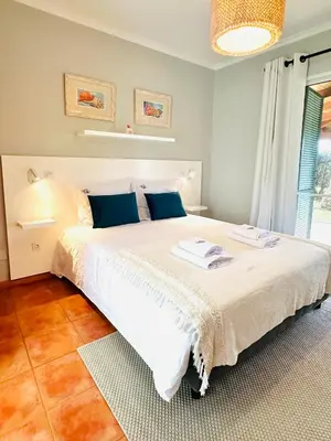 a bedroom with a large white bed with blue pillows at Quinta do Ribeiro Salgado's Beach House in Porto Santo