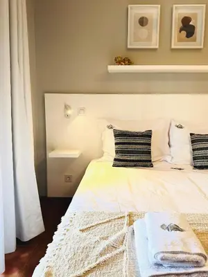 a bed with white sheets and pillows in a bedroom at Quinta do Ribeiro Salgado's Beach House in Porto Santo