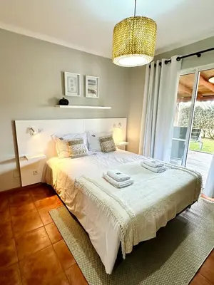 a bedroom with a large white bed with a chandelier at Quinta do Ribeiro Salgado's Beach House in Porto Santo