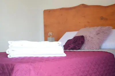 a bed with white sheets and purple pillows on it at Angel's Apartment in Funchal