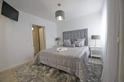 a white bedroom with a large bed and a television at Villa Golden Charm in Tábua