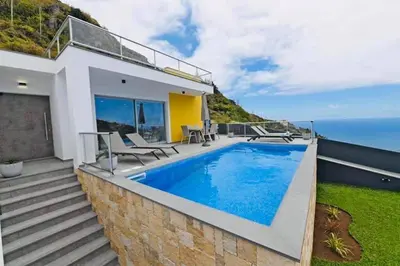 a house with a swimming pool and the ocean at Villa Golden Charm in Tábua