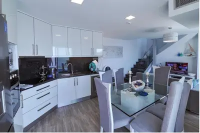a kitchen with a glass table and white cabinets at Villa Atlantic Charm in Venda do Atalhinho
