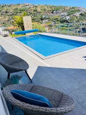 a swimming pool with a wicker chair and a table and a chair at Villa Atlantic Charm in Venda do Atalhinho