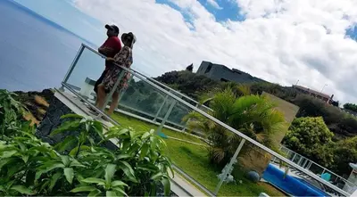 two people standing on a glass walkway near a house at Villa Atlantic Charm in Venda do Atalhinho