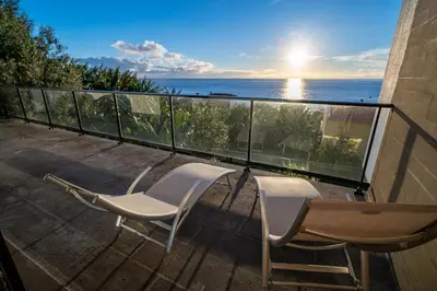 a balcony with two chairs and a view of the ocean at Beach Sunset Villa 100m from Ocean & Beach in Paul do Mar