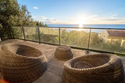a balcony with three wicker chairs and the ocean at Beach Sunset Villa 100m from Ocean & Beach in Paul do Mar